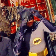 a man in a batman costume is standing in front of a red shelf