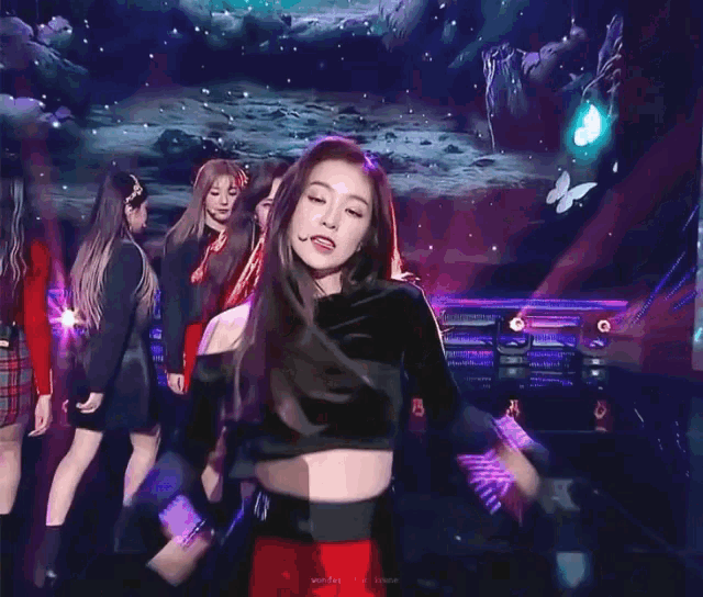a group of girls are standing on a stage with a purple light shining on them