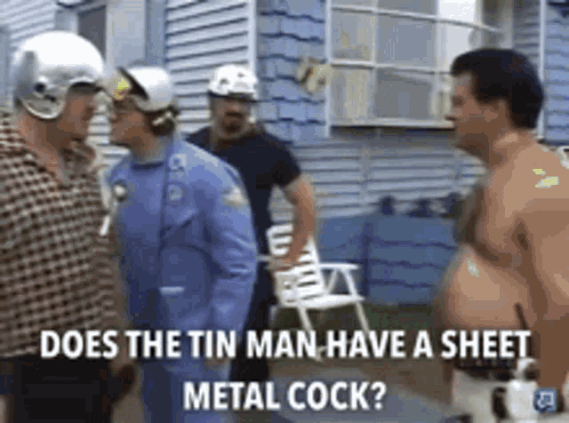 a group of men are standing outside of a house and one of them has a metal cock on his chest .