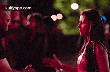 a man and a woman are standing next to each other in a crowd at a party .