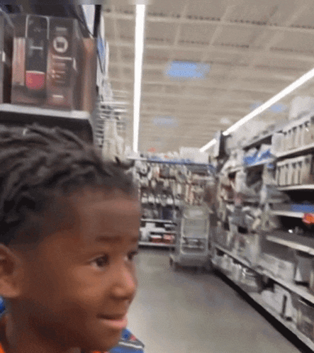 a young boy in a store looking at something on a shelf with the word lollipop on it