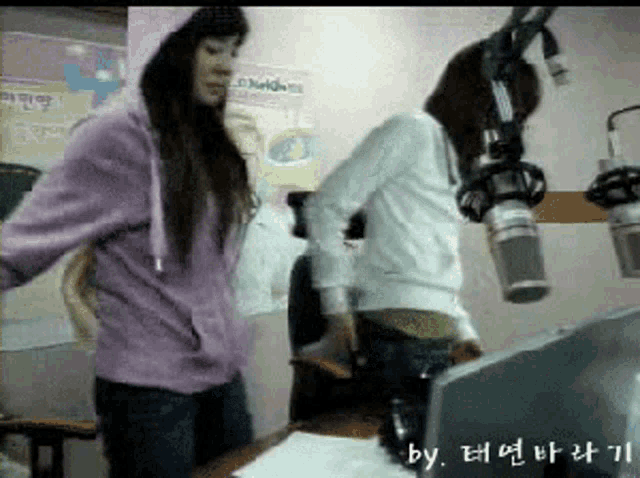 a woman in a purple hoodie is standing next to another woman in a white jacket