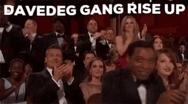 a group of people are sitting in a theatre applauding and watching a movie .