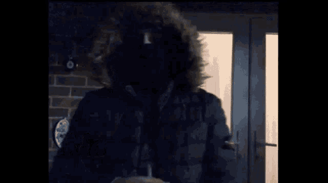 a man wearing a mask and a fur hood is standing in front of a door with the words sokaklarda geçti written below