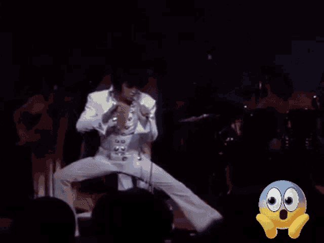a close up of a man singing into a microphone with a surprised face in the background