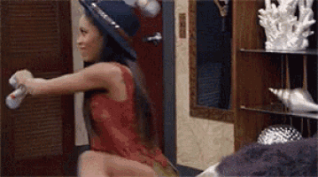 a woman in a red dress is holding a bottle of spray in her hand in a room .