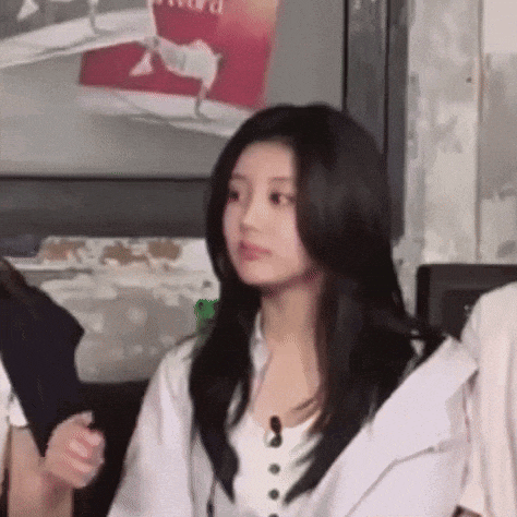 a woman with long black hair is wearing a white shirt and a white jacket .