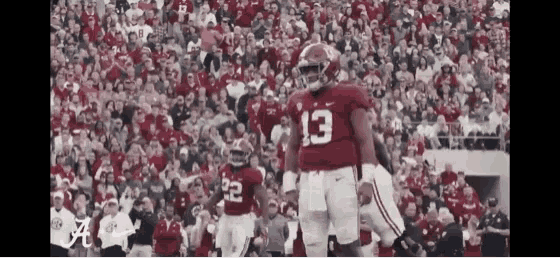 a football player with the number 13 on his jersey is standing in front of a crowd of people .