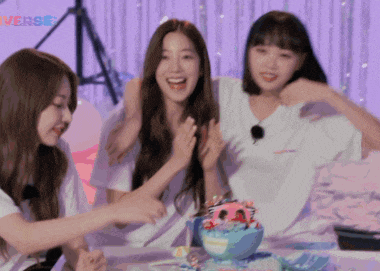 three girls are sitting at a table with a bowl of ice cream