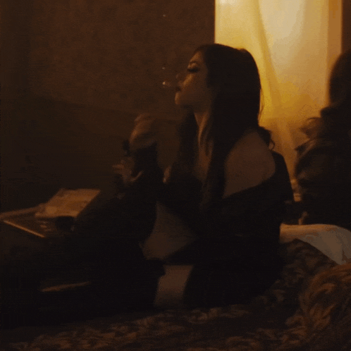a woman is smoking a cigarette in a dark room