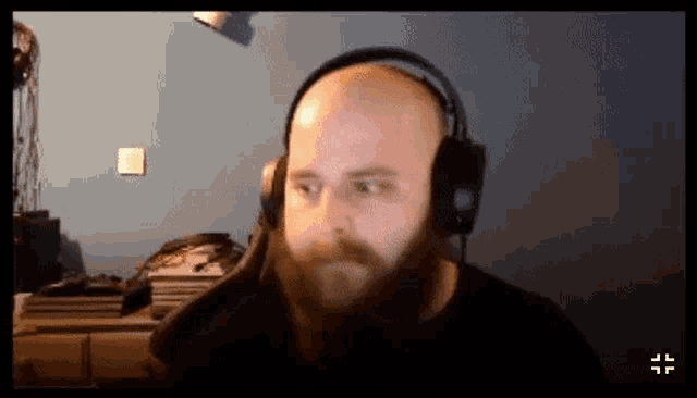 a man with a beard is wearing headphones and looking at the camera .