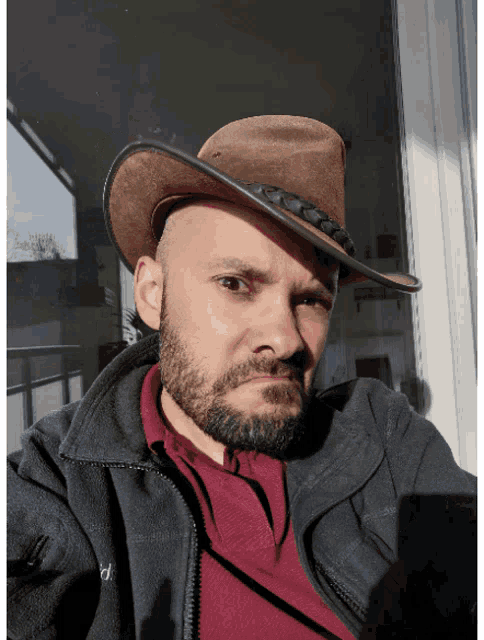 a man with a beard wearing a cowboy hat and a jacket