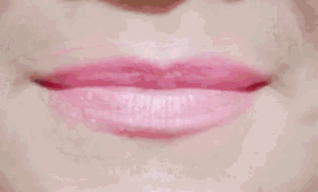a close up of a woman 's lips with pink lipstick licking her tongue .