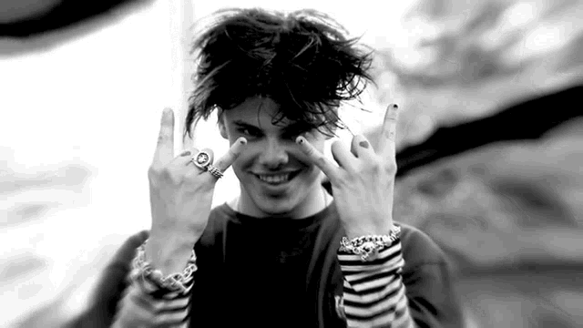 a black and white photo of a young man wearing rings