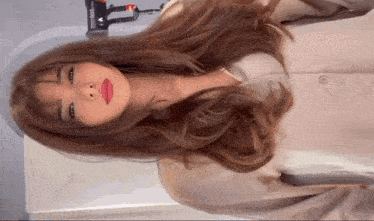 a woman with long brown hair is wearing a tan shirt