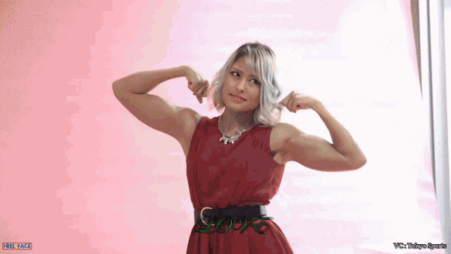 a woman in a red dress is flexing her muscles in front of a pink background with the word love on it