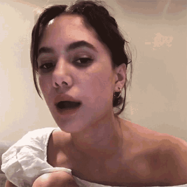a close up of a woman 's face with a white top on