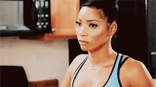 a woman in a blue tank top is looking at something in a kitchen
