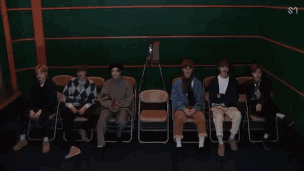 a group of young men are sitting in folding chairs in a dark room