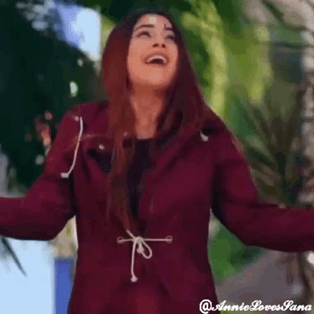 a woman in a maroon jacket is surrounded by confetti and flowers