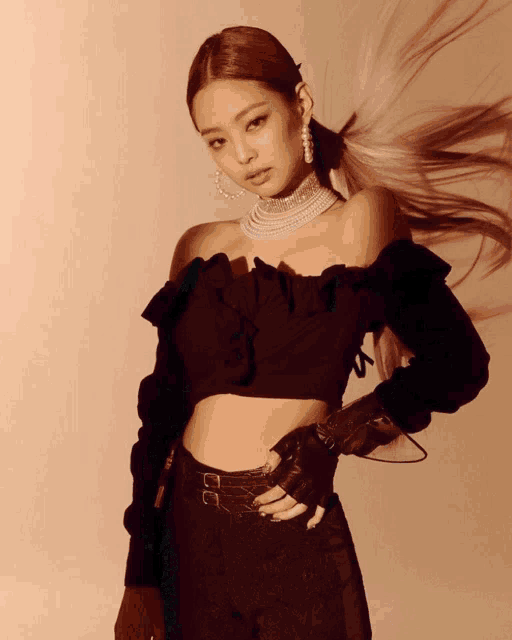 a woman wearing a black off the shoulder top and a pearl choker