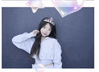 a woman wearing a tiara and a white sweatshirt is standing in front of a blue wall .