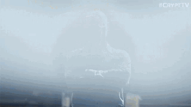 a man with his arms crossed is standing in a foggy room with his face visible .