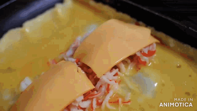 a piece of cheese is being added to a casserole dish with crab meat