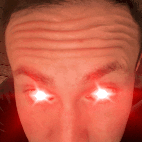 a close up of a man 's forehead with bright red eyes