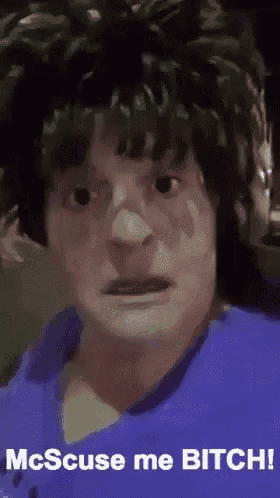 a man with a wig on his head is making a funny face with the words `` mcscuse me bitch '' .
