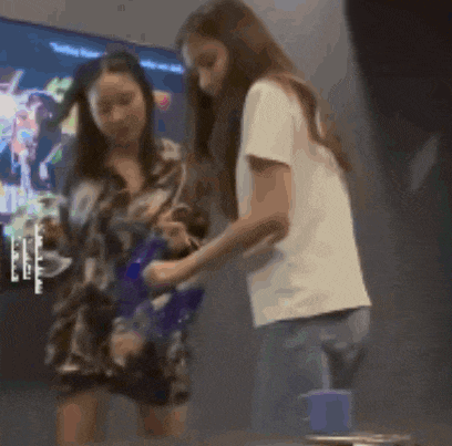 two women are standing next to each other and one is holding a blue bag
