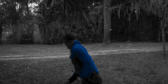 a man in a blue jacket is throwing a frisbee in the air