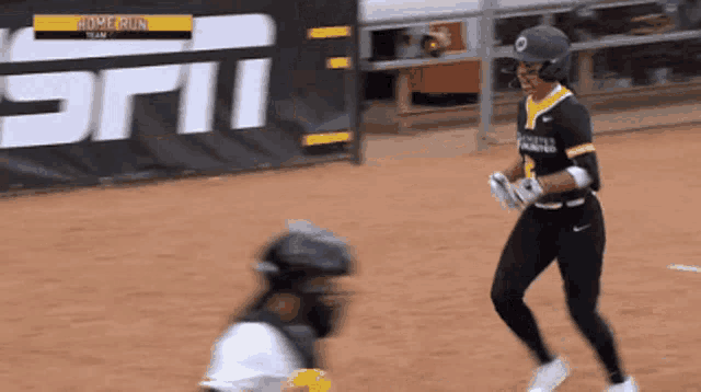 a baseball player runs towards a catcher in front of an espn banner