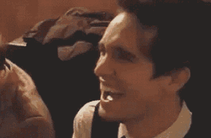 a man in a suit and tie is clapping his hands in a room .