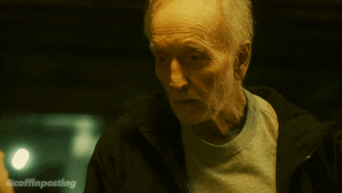 an older man with a beard is standing in a dark room with the hashtag coffinposting