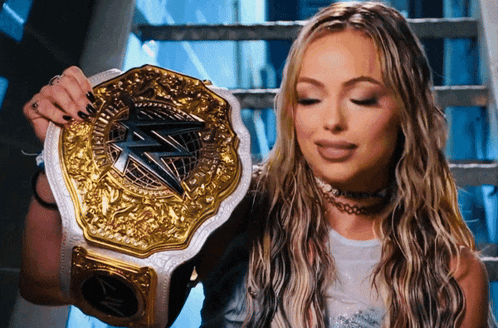 a woman is holding a gold and silver championship belt