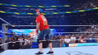 a wrestler in a red shirt is walking out of a wrestling ring .
