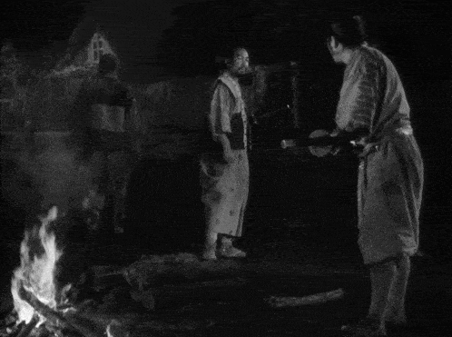 a group of men are standing around a fire in a black and white photo