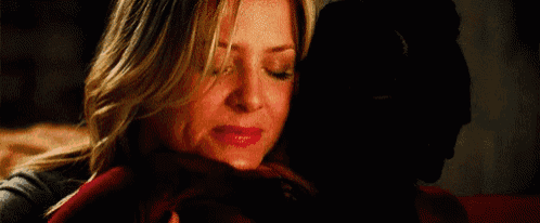 a woman is hugging a man in a dark room and holding his face .