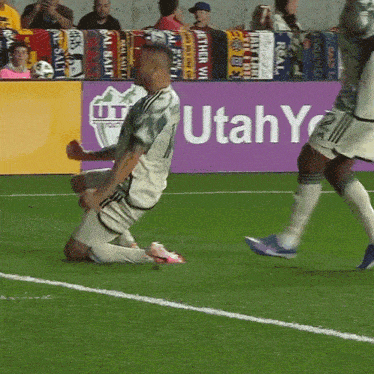 a soccer player kneels on the field in front of a utah advertisement