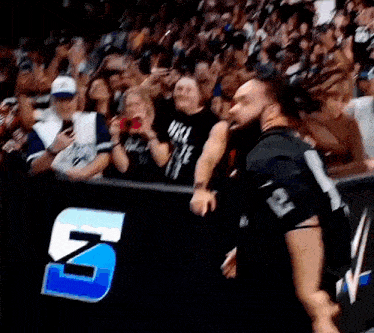 a man in a black shirt with the number 12 on it is standing in front of a crowd of people .