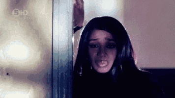 a woman with long hair is leaning against a wall .