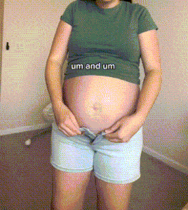 a pregnant woman wearing shorts and a green shirt with the words um and um on her belly