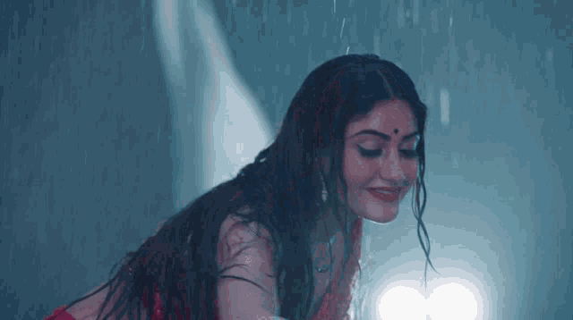 a woman in a red dress is standing in the rain with her hair wet .