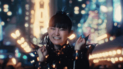 a woman is dancing in front of a crowd in a city at night