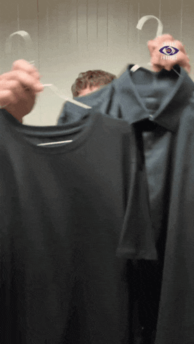 a man is holding a shirt with a blue eye on it