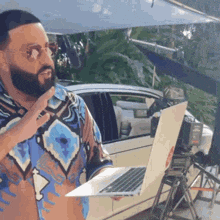 a man with a beard is holding a laptop and speaking into a microphone .