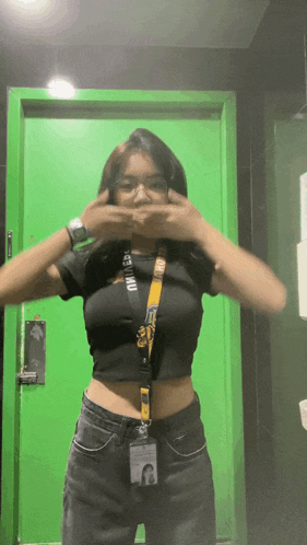 a woman standing in front of a green door covering her face with her hands .