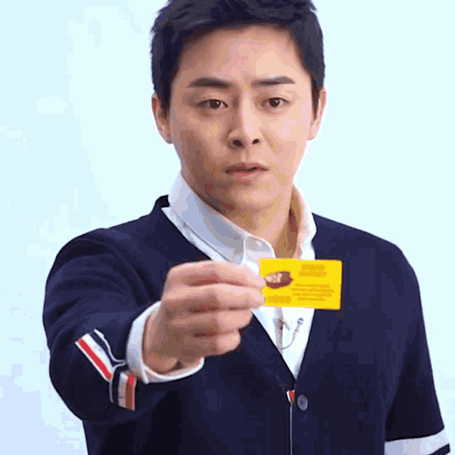 a man in a blue jacket is holding a yellow card that says " passport " on it