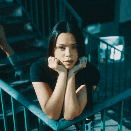 a woman leaning on a railing with a tattoo on her wrist that says ' i love you '